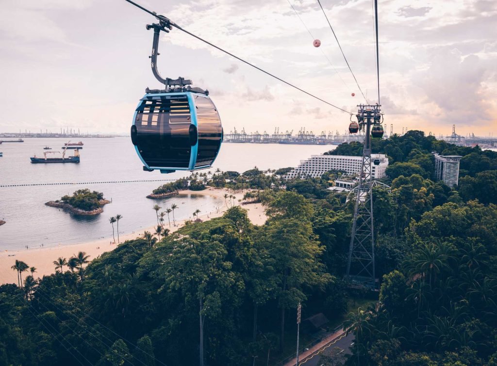 Singapore Cable Car gliding above greenery and water, offering panoramic views of the city’s landscape and coastal areas.