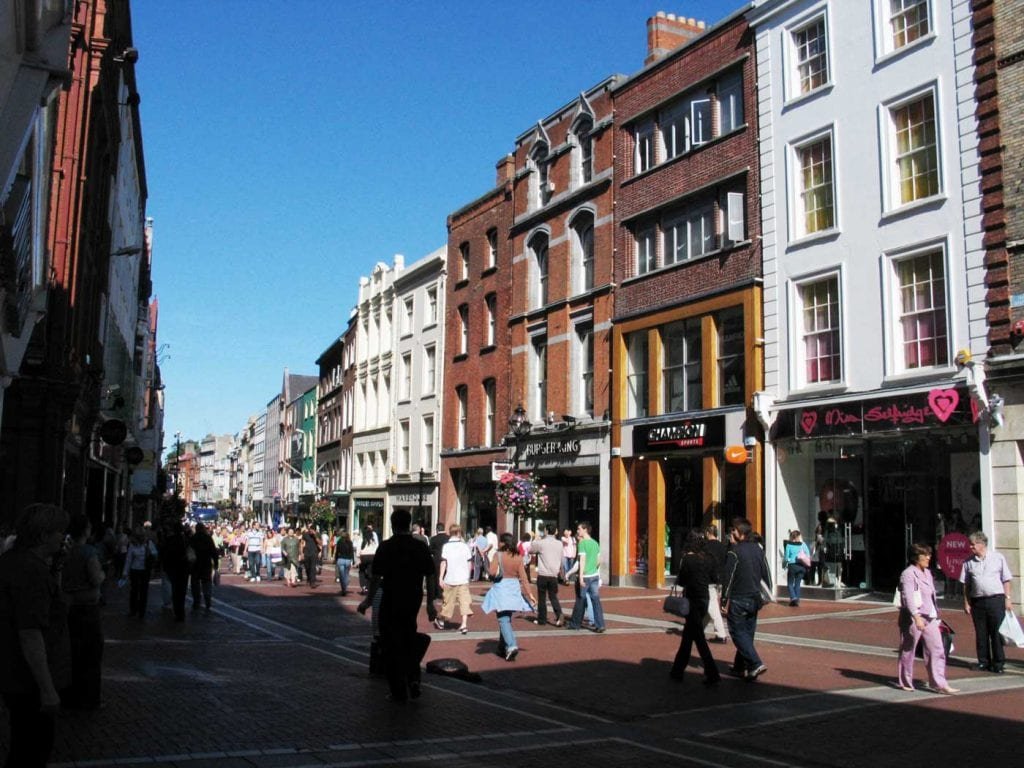 A busy shopping street in Dublin under a blue sky.