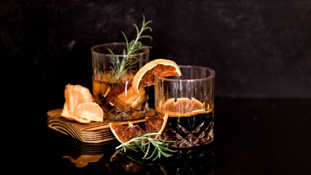 Image of two glasses with dark liquor and fruit 