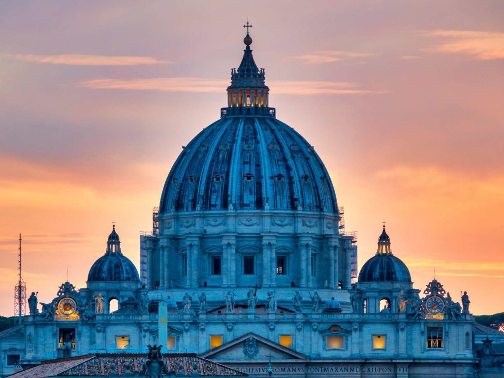St. Peter’s Basilica in Vatican City at sunset, with its iconic dome glowing against a colorful sky in Rome’s skyline.