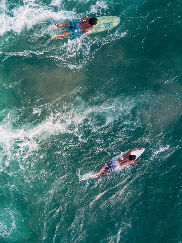 Drone view of two people surfing in the ocean near Bali.
