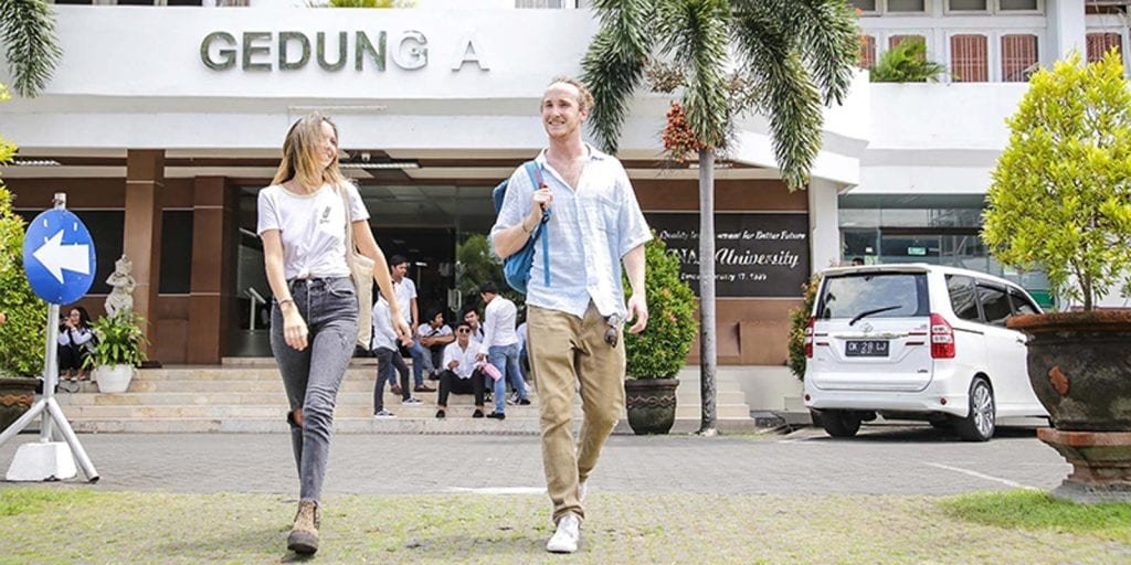 students walking outside on the campus of undiknas university